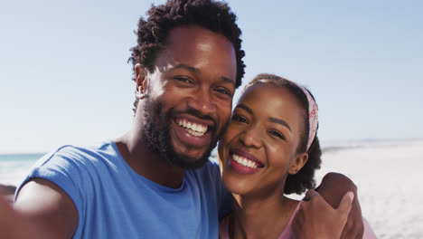 Portrait-of-african-american-couple-smiling-to-camera-on-the-beach