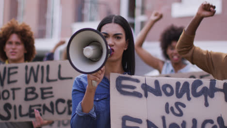 Grupo-Diverso-De-Hombres-Y-Mujeres-Sosteniendo-Pancartas-Gritando-Usando-Megáfono-Durante-La-Protesta