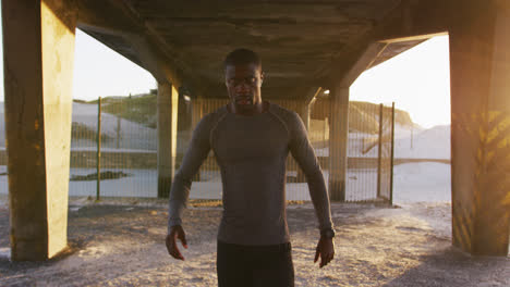 Portrait-of-focused-african-american-man-walking-to-camera,-exercising-outdoors-in-the-evening