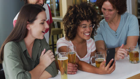 Eine-Vielfältige-Gruppe-Glücklicher-Freunde-Trinkt-Bier-Und-Benutzt-Smartphones-In-Einer-Bar
