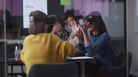 Diverse-work-colleagues-sitting-in-meeting-room-wearing-virtual-reality-glasses