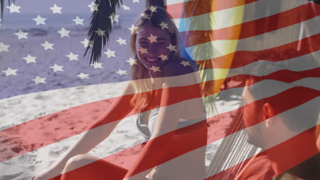 Animation-of-american-flag-waving-over-couple-in-deckchairs-laughing-on-beach