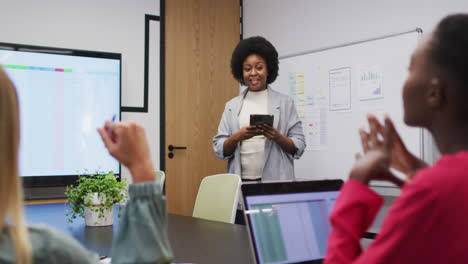 African-american-businesswoman-using-tablet-presenting-to-female-colleagues-at-office-meeting