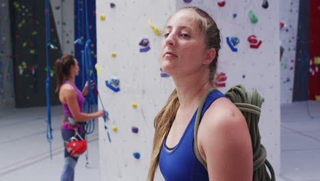 Portrait-of-caucasian-woman-with-rope-on-her-back-turning-to-camera-at-indoor-climbing-wall