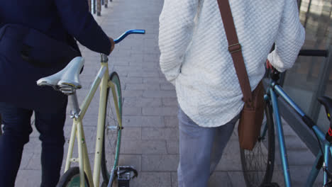 Zwei-Verschiedene-Männliche-Freunde-Gehen-Zusammen-Mit-Fahrrädern-Auf-Der-Straße-Spazieren