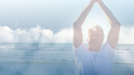 Animation-of-glowing-light-over-happy-senior-man-practicing-yoga-by-seaside
