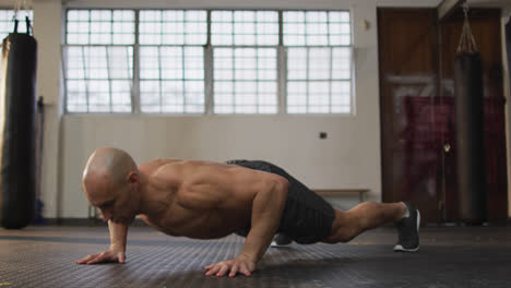 Caucasian-muscular-shirtless-bald-man-exercising,-doing-push-ups