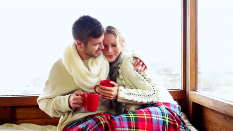 Cute-couple-relaxing-together-under-a-blanket-in-their-ski-lodge