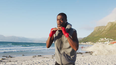 Hombre-Afroamericano-Enfocado-En-Boxeo,-Haciendo-Ejercicio-Al-Aire-Libre-Junto-Al-Mar