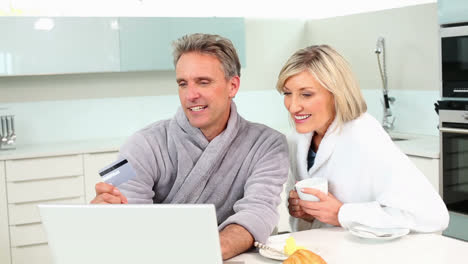 Mature-couple-shopping-online-at-breakfast