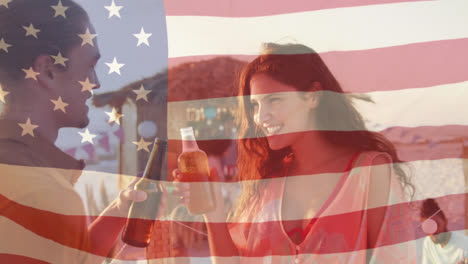 Animation-of-american-flag-waving-over-man-and-woman-making-toast-with-beer-bottles-on-beach