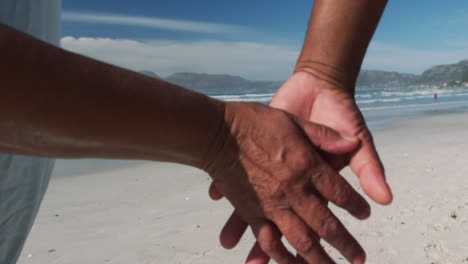 Mittelteil-Eines-älteren-Afroamerikanischen-Paares,-Das-Am-Strand-Spazieren-Geht-Und-Händchen-Hält