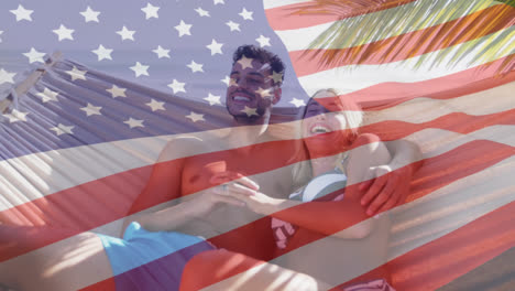 Animation-of-american-flag-waving-over-smiling-couple-in-love-in-hammock-on-beach