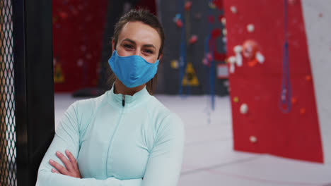 Portrait-of-smiling-caucasian-woman-wearing-face-mask-at-an-indoor-climbing-gym
