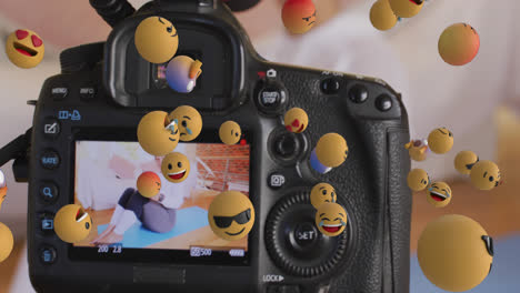 Animation-Von-Emojis-über-Dem-Kamerabetrachter-Mit-Einer-Fitness-Vloggerin,-Die-Zu-Hause-Trainiert