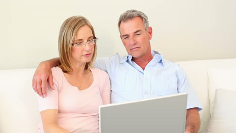 Älteres-Paar-Schaut-Gemeinsam-Auf-Der-Couch-Auf-Den-Laptop