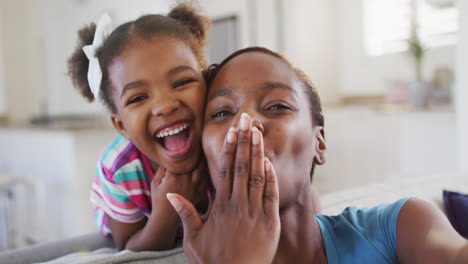 Feliz-Madre-E-Hija-Afroamericana-Tomándose-Selfie-Dando-Besos-Al-Aire-En-Casa
