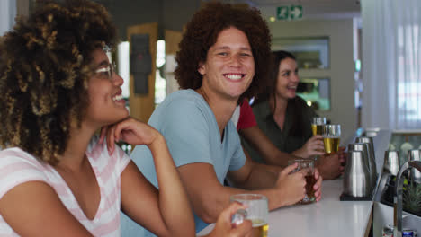 Eine-Vielfältige-Gruppe-Glücklicher-Freunde,-Die-In-Einer-Bar-Bier-Trinken-Und-Lächeln
