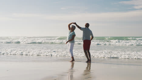 Senior-african-american-couple-smiling-and-dancing-at-the-beach