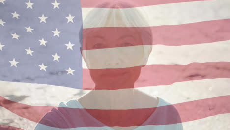 Animation-of-american-flag-waving-over-portrait-of-senior-woman-on-beach