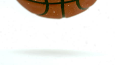 Animation-of-snowflakes-falling-over-bouncing-basketball,-on-white-background