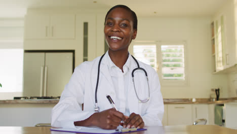 Lächelnde-Afroamerikanische-Ärztin,-Die-Sich-Während-Einer-Videoanruf-Beratung-Notizen-Macht