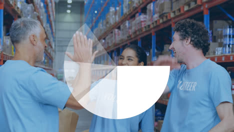 Pie-graph-against-team-of-diverse-volunteers-high-fiving-each-other-at-warehouse