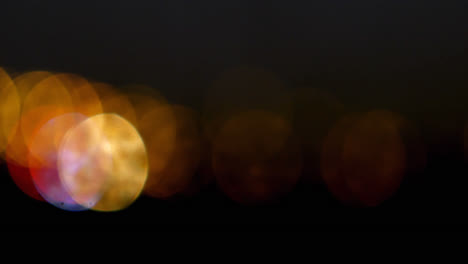 Spots-of-yellow-and-red-bokeh-lights-blinking-against-black-background