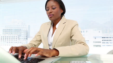 Businesswoman-talking-on-phone-and-using-laptop-at-desk