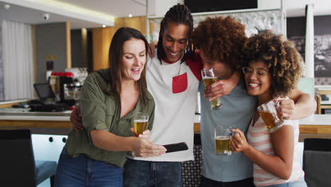 Diverse-group-of-happy-friends-drinking-beers-and-taking-a-selfie-at-a-bar