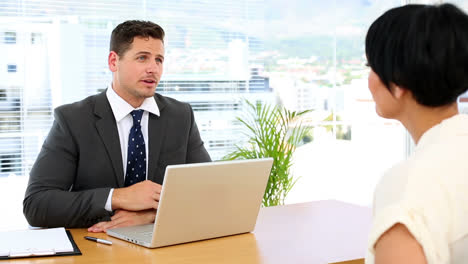 Handsome-businessman-with-laptop-interviewing-a-woman