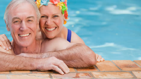 Portrait-of-smiling-caucasian-senior-couple-on-holiday-in-swimming-pool