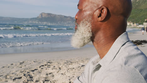 Hombre-Afroamericano-Mayor-Sentado-En-La-Playa,-Admirando-La-Vista