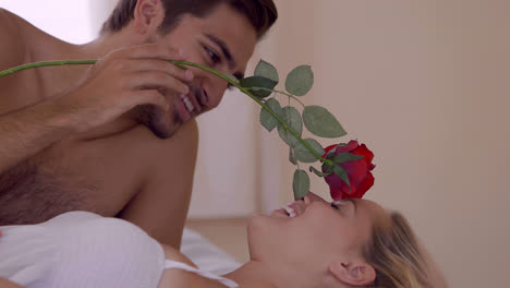 Man-tickling-his-girlfriend-with-a-red-rose-on-bed