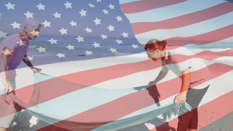 Animation-of-american-flag-waving-over-senior-couple-spreading-blanket-on-beach
