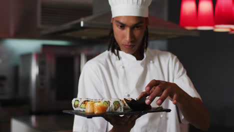 Mixed-race-male-chef-standing-in-kitchen-making-a-nice-plate-of-sushi