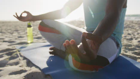 Mittelteil-Eines-Afroamerikanischen-Mannes,-Der-Am-Strand-Yoga-Praktiziert-Und-Im-Freien-Am-Meer-Trainiert