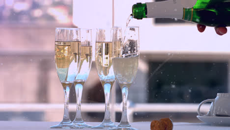 Animation-of-white-particles-floating-over-champagne-bottle-being-poured-into-four-glasses