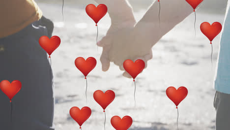Animation-Von-Digitalen-Symbolen-Mit-Roten-Herz-Liebesballons-über-Einem-Paar,-Das-Am-Strand-Händchen-Hält