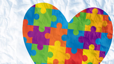 Animation-of-heart-in-autism-awareness-month-puzzles-over-crumpled-paper