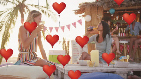 Animation-of-red-heart-love-balloons-digital-icons-over-friends-having-drinks-in-beach-bar
