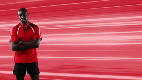 Animation-of-rugby-player-standing-with-arms-crossed-over-glowing-red-light-trails-background