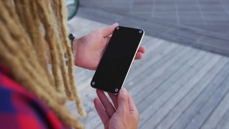 Mixed-race-man-with-dreadlocks-standing-in-the-street-using-smartphone