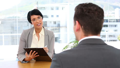 Businesswoman-interviewing-man-at-her-desk