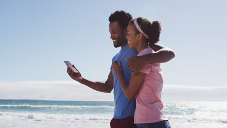 African-american-couple-smiling-taking-selfie-with-smartphone-on-the-beach