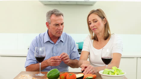 Mature-couple-drinking-red-wine-together-and-making-a-salad