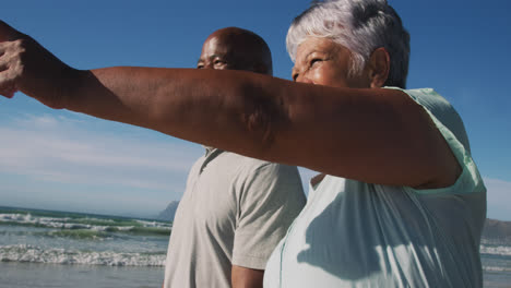 Lächelndes-älteres-Afroamerikanisches-Paar,-Das-Am-Strand-Spazieren-Geht-Und-Händchen-Hält