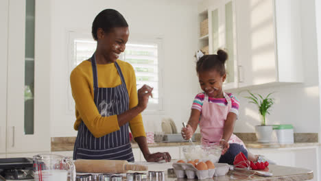 Feliz-Madre-E-Hija-Afroamericana-Usando-Delantales-Divirtiéndose-Mientras-Cocinan-En-La-Cocina