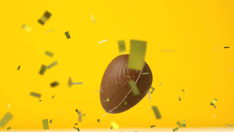 Animation-of-gold-confetti-and-chocolate-easter-egg-falling-and-bouncing-on-yellow-background