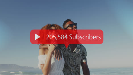 Animation-of-speech-bubble-with-subscribers-and-numbers-over-smiling-couple-embracing-on-beach